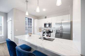 A modern kitchen with a white countertop and blue chairs.